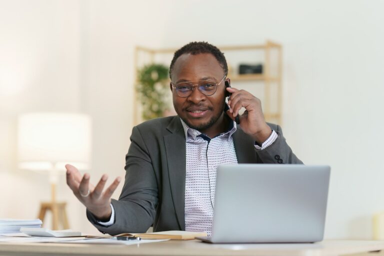 Smiling American African Banker or Accountant talking phone with client and makes financial report